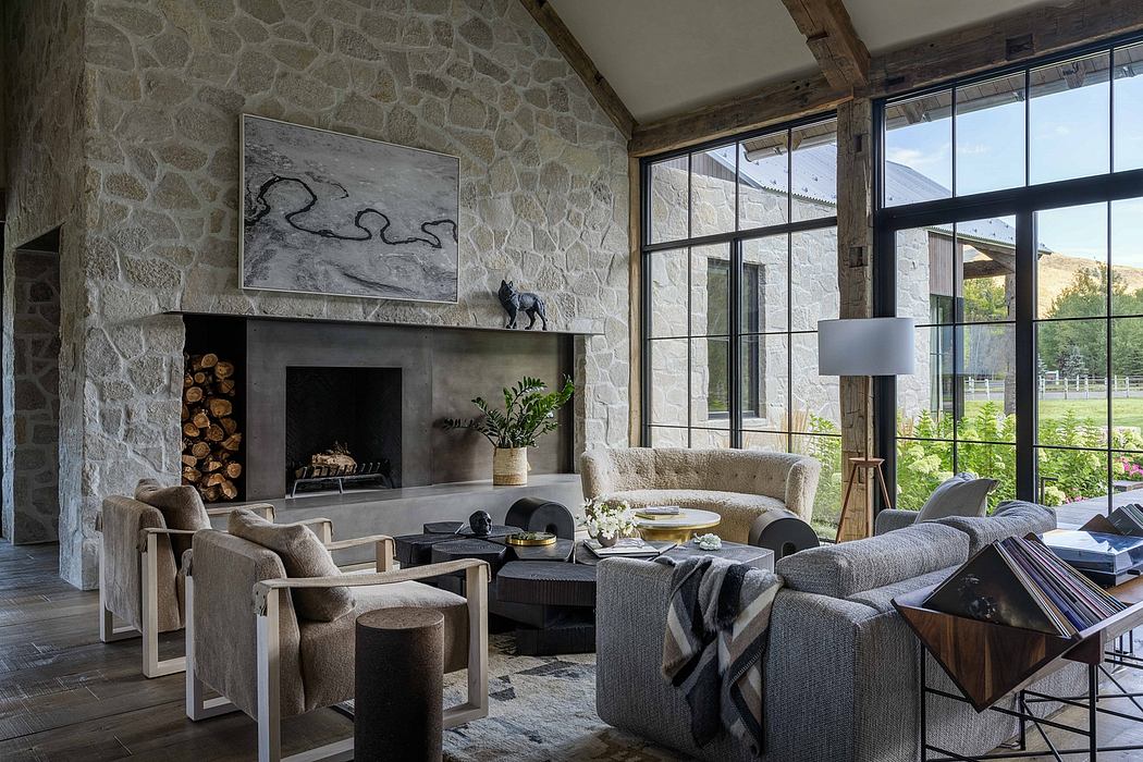 Rustic stone walls, cozy fireplace, large windows, and modern furnishings create a warm, inviting space.