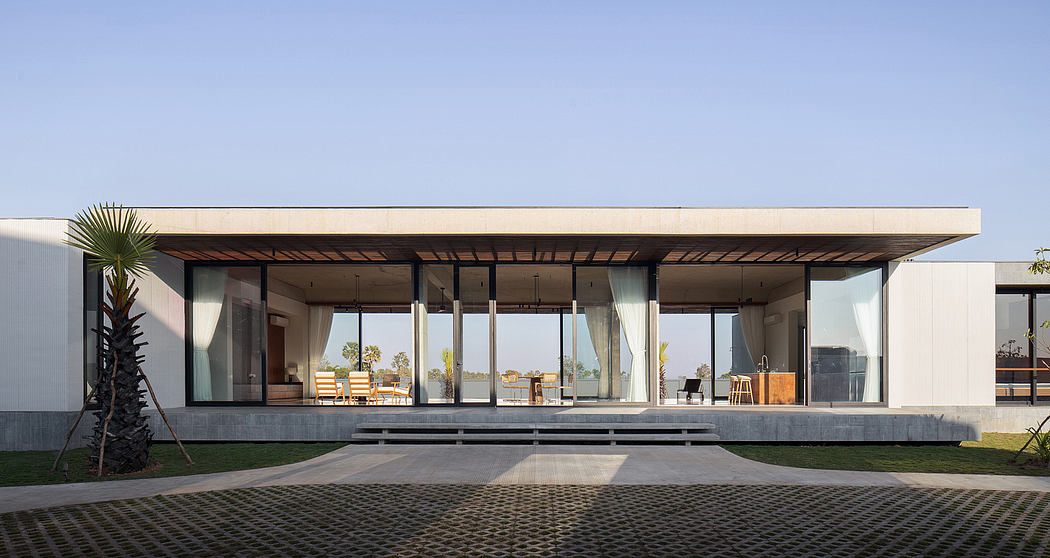 Minimalist modern architecture with expansive glass walls, wooden beams, and tropical plants.