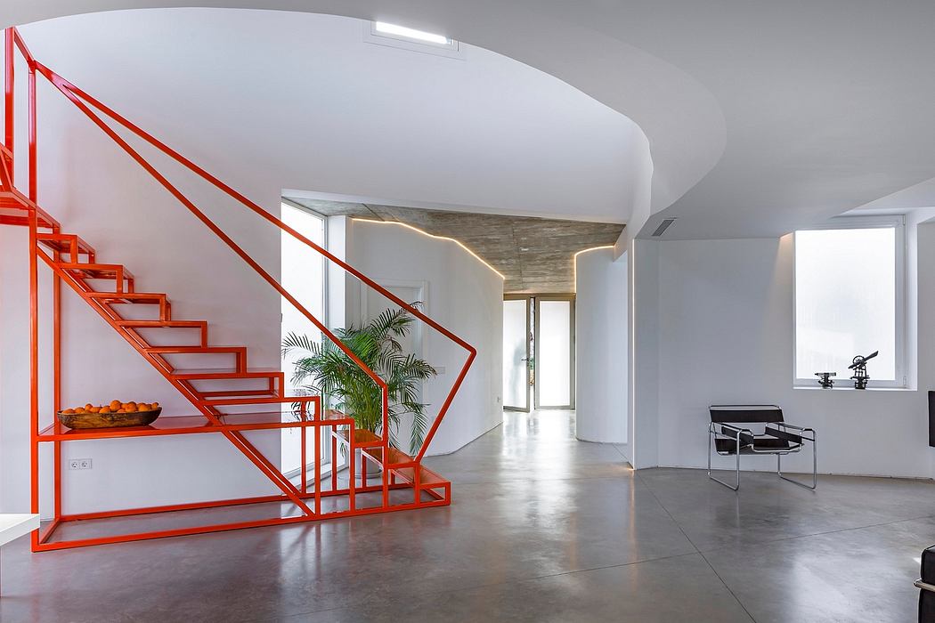 Modern, open-plan interior with bold red stairs, sleek furnishings, and natural lighting.