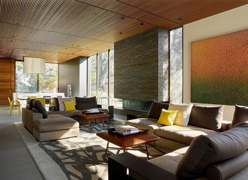 Expansive living space with wood-paneled ceiling, stone wall, modular sofas, and geometric rug.