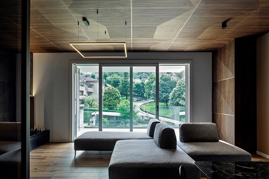 Sleek modern interior with expansive windows overlooking lush greenery and a curved sofa.