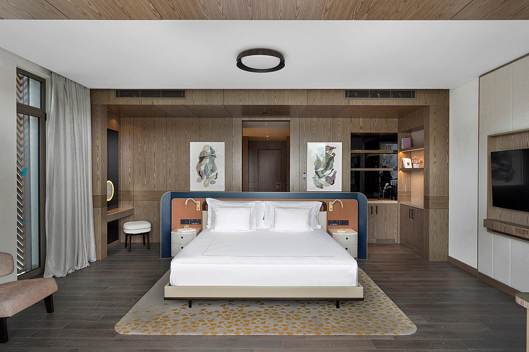 Modern bedroom with wooden paneled walls, minimalist furnishings, and abstract artwork.