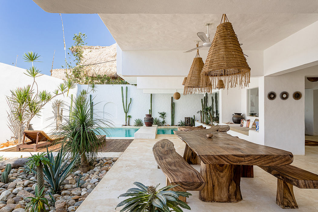Rustic outdoor dining area with thatched ceiling, cacti, and wooden furniture.