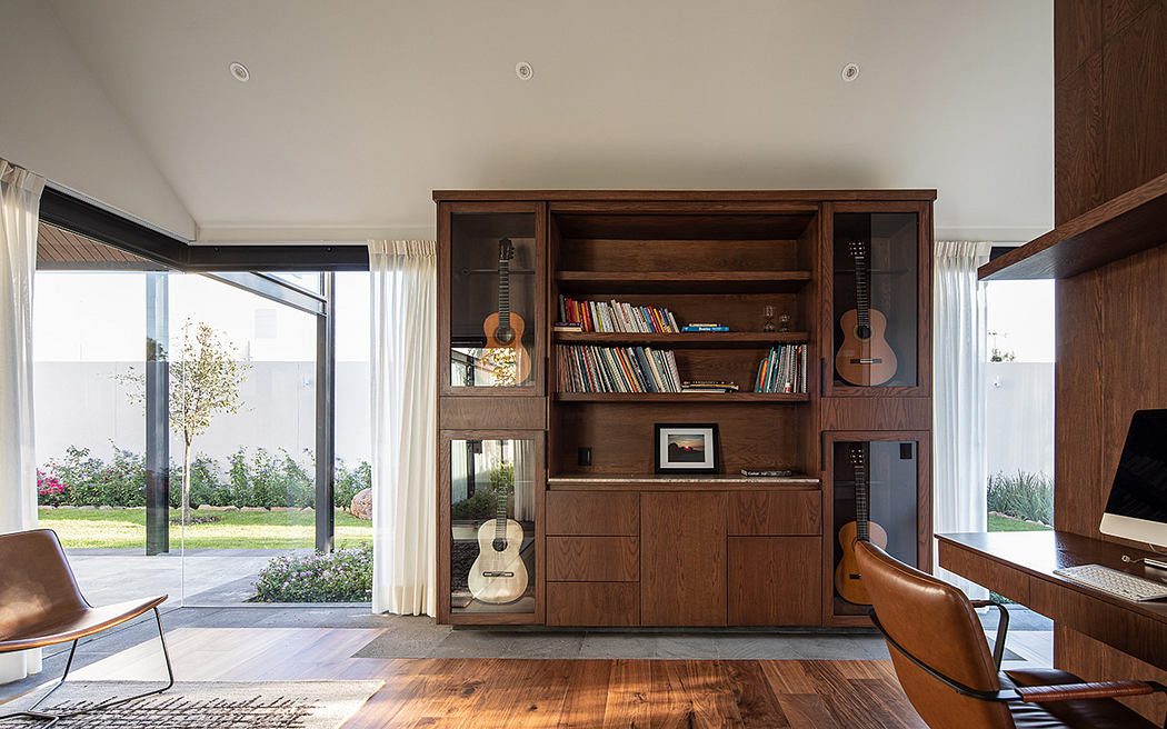 Warm wooden built-in shelving and cabinetry, cozy seating, and expansive windows overlooking garden.