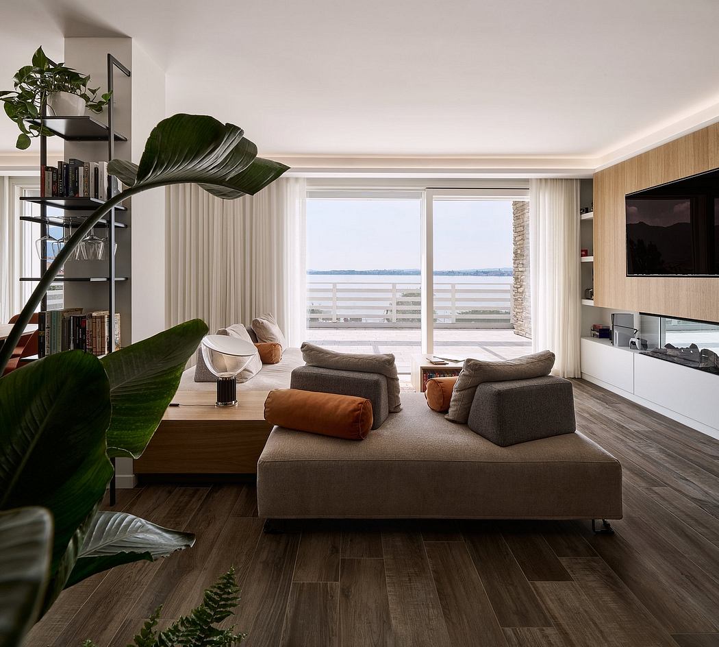 Spacious living room with large windows, modern furniture, and lush indoor plants.