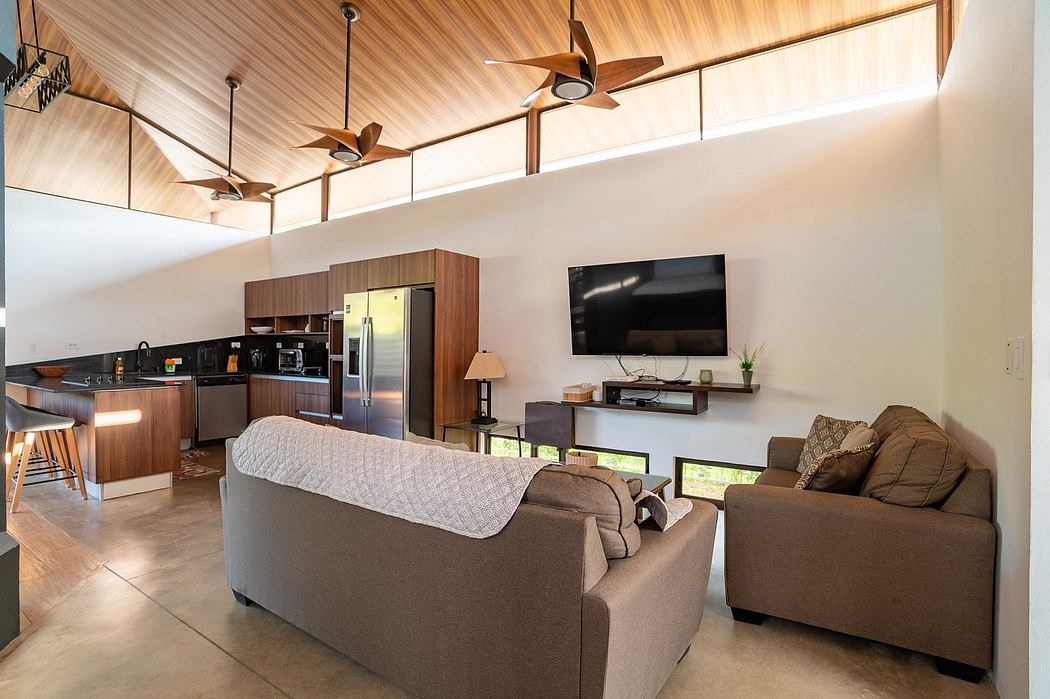 Modern, open-concept living space with wooden ceiling, pendant lighting, and sleek kitchen.