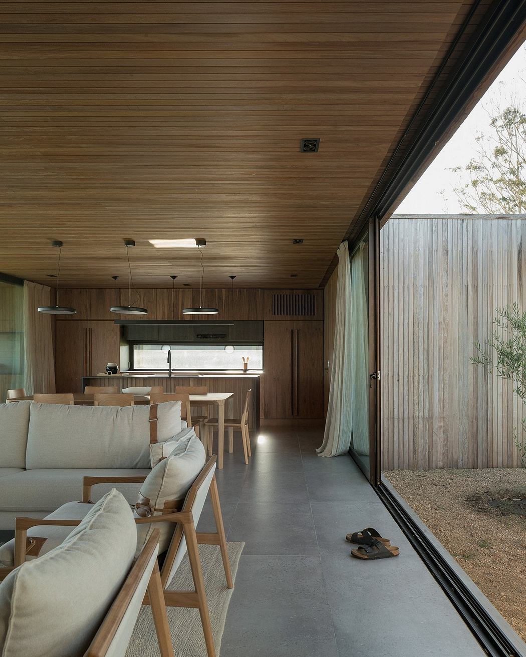 A modern and minimalist living space with wooden panels, large windows, and a sleek interior design.