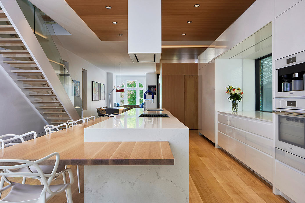 Bright, open-plan kitchen-dining area with modern wood and white accents, glass wall.