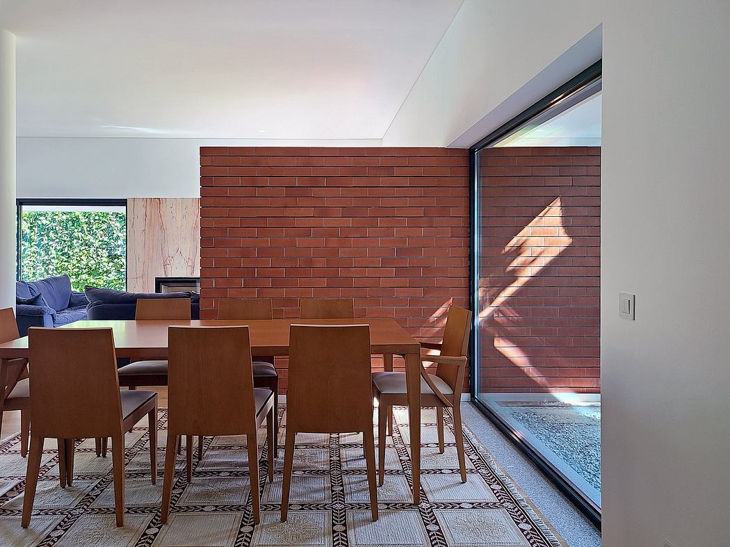 A modern dining area with a brick accent wall, large windows, and wooden furniture.