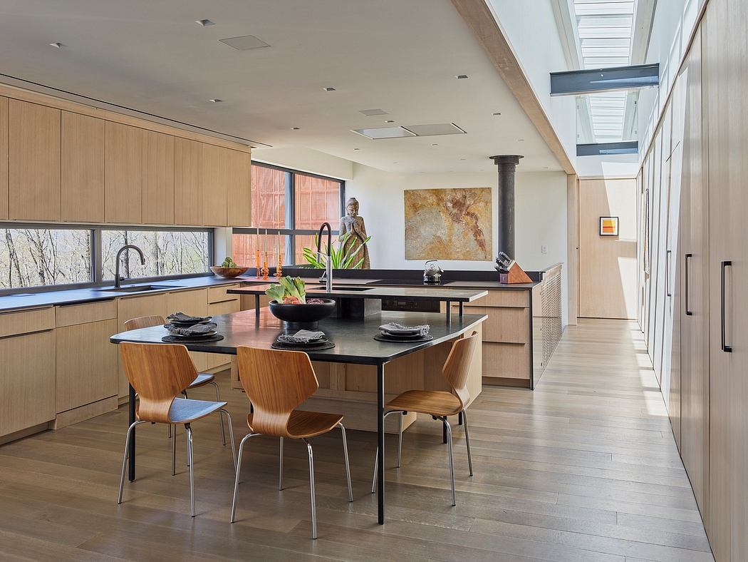 Spacious modern kitchen with wood cabinets, black countertops, and a large dining table.