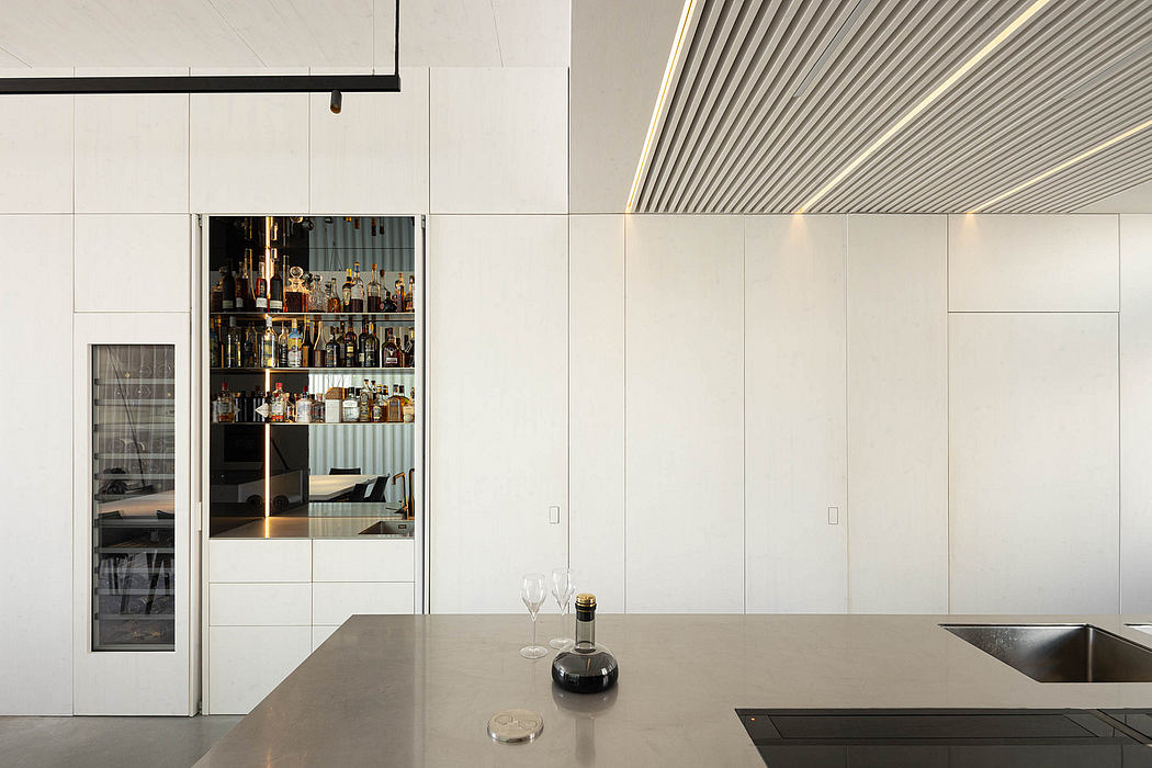 Sleek, minimalist kitchen with built-in bar and glass-enclosed liquor display cabinet.