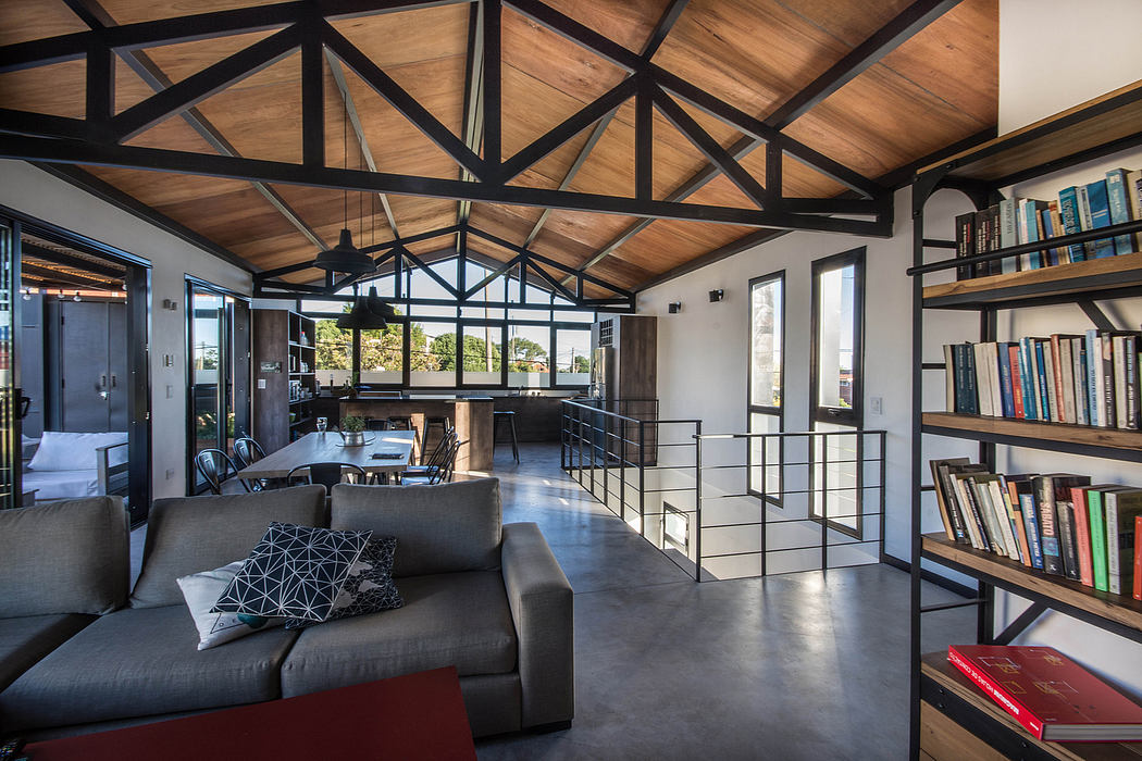 A loft-style room with an exposed wooden ceiling, metal accents, and built-in bookshelves.