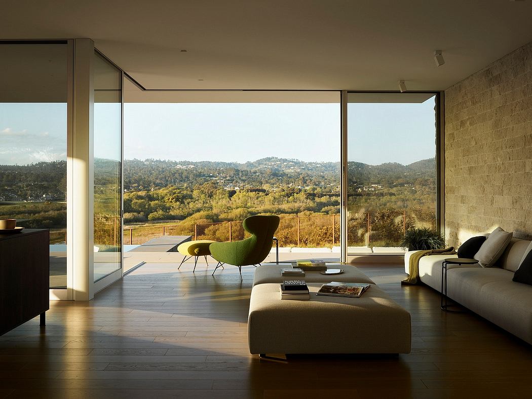 Minimalist modern living room with floor-to-ceiling windows overlooking a scenic landscape.