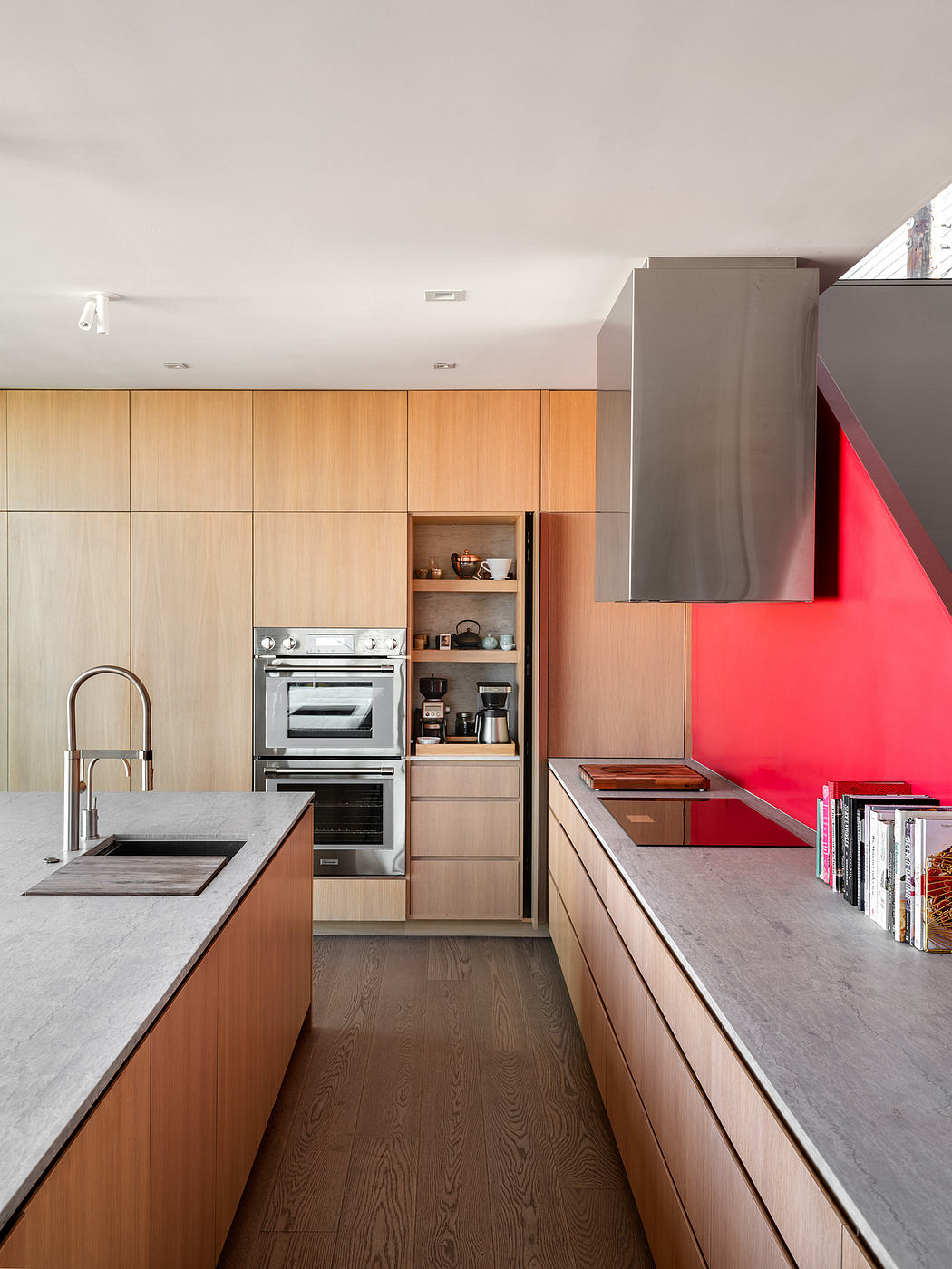 Modern kitchen with sleek wood cabinetry, stone countertops, and vibrant red accents.