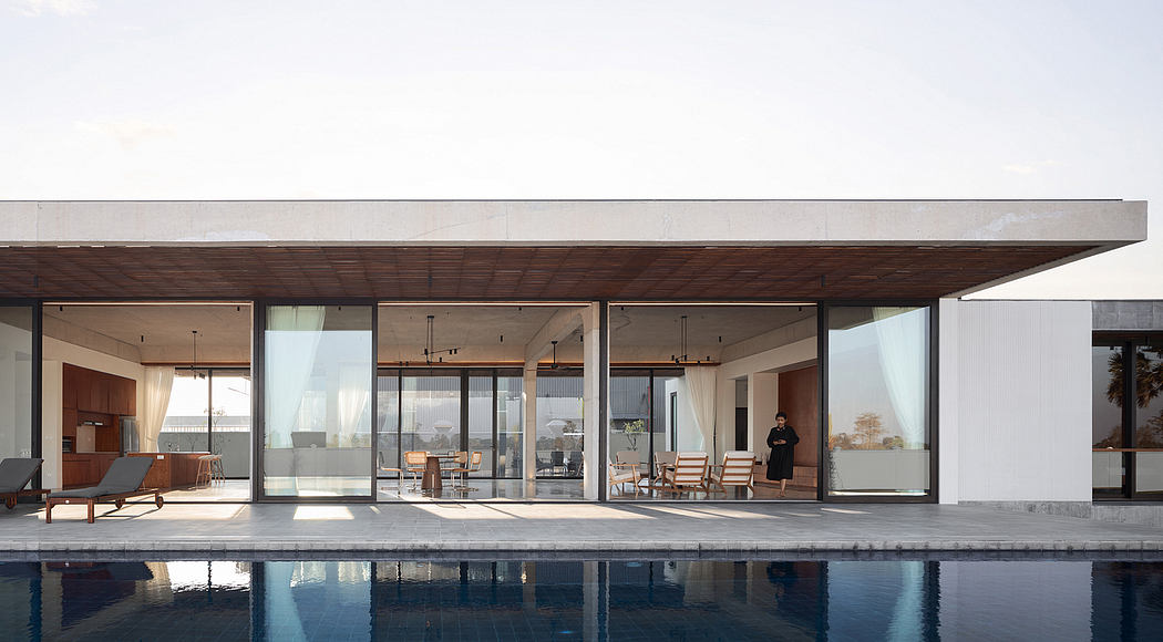 Contemporary architectural design with expansive glass walls, wooden ceilings, and a pool reflecting the surroundings.