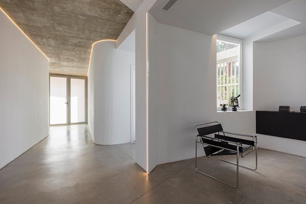 Minimalist room with concrete ceiling, sleek black chairs, and a large window overlooking nature.
