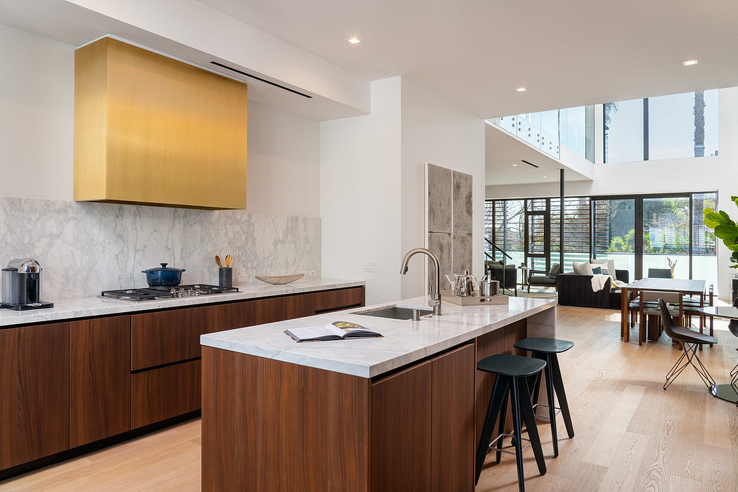 Modern kitchen with sleek wood cabinets, marble countertops, and a striking gold-toned hood.