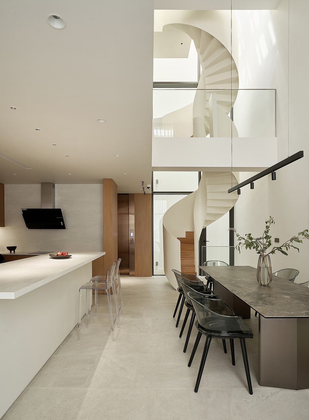 A sleek, modern kitchen and dining area with a spiral staircase, minimalist furniture, and natural lighting.