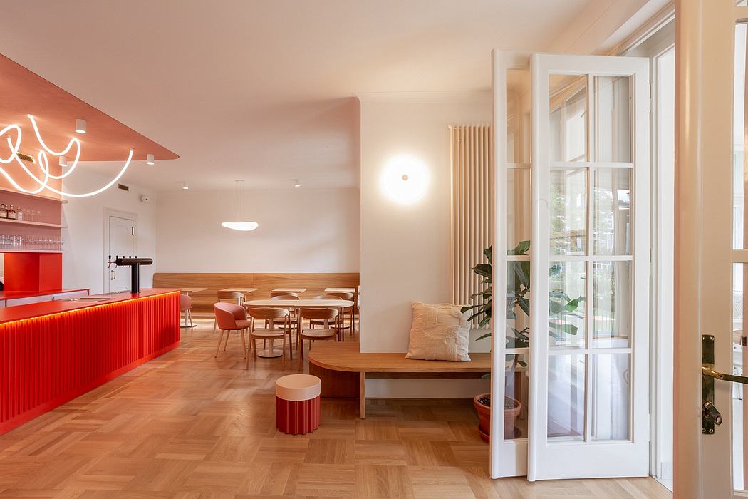 Vibrant, modern interior with wood floors, red accents, and large windows creating a warm, inviting space.