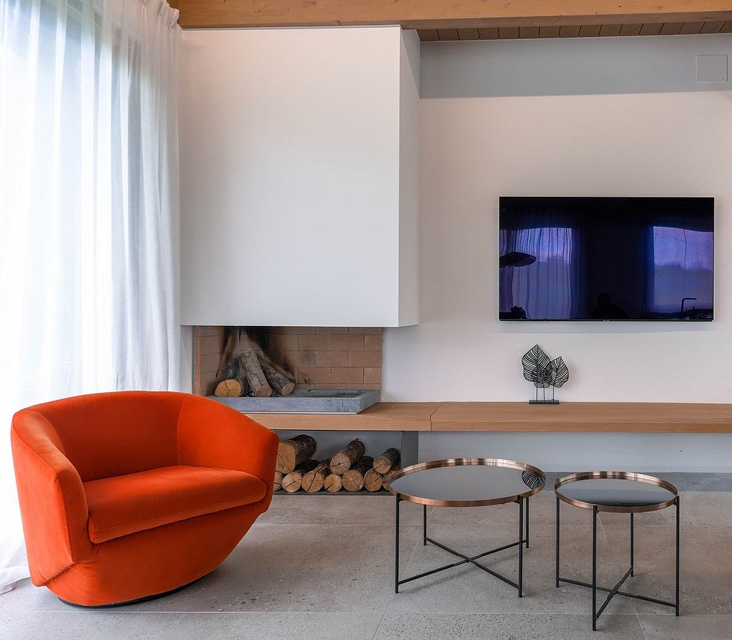Cozy cabin-like living room with fireplace, orange velvet swivel chair, and minimalist coffee tables.