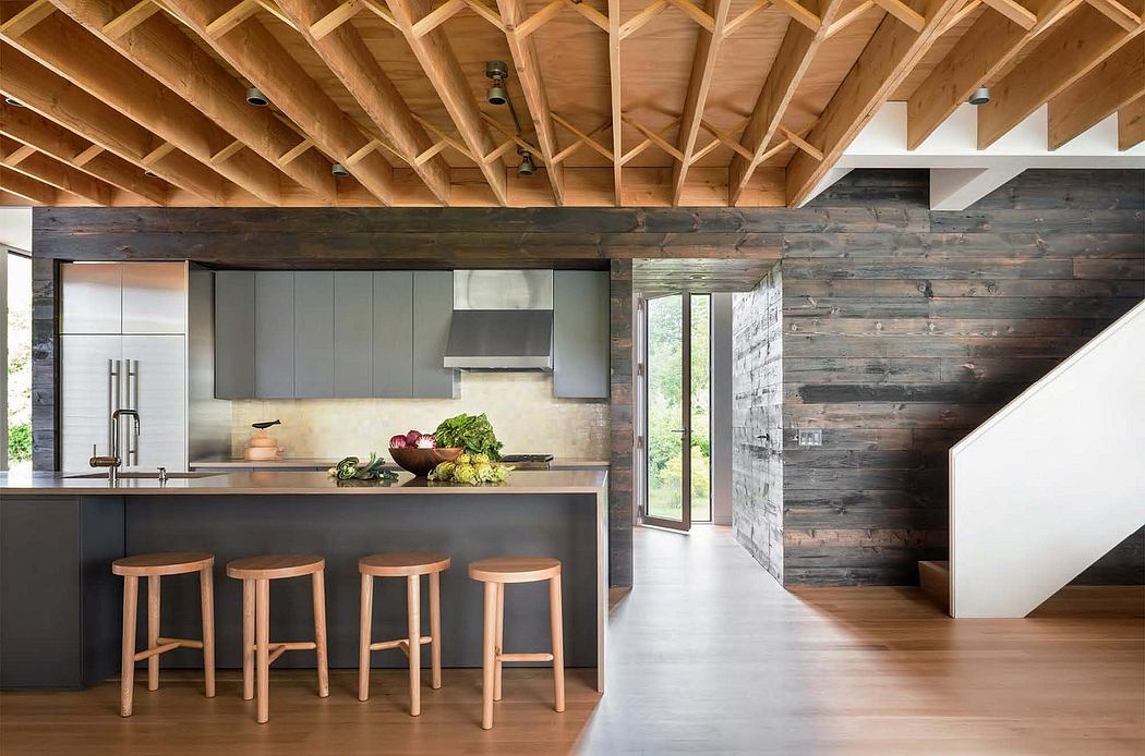A modern kitchen with a wooden ceiling, gray cabinetry, and a rustic wood wall backdrop.