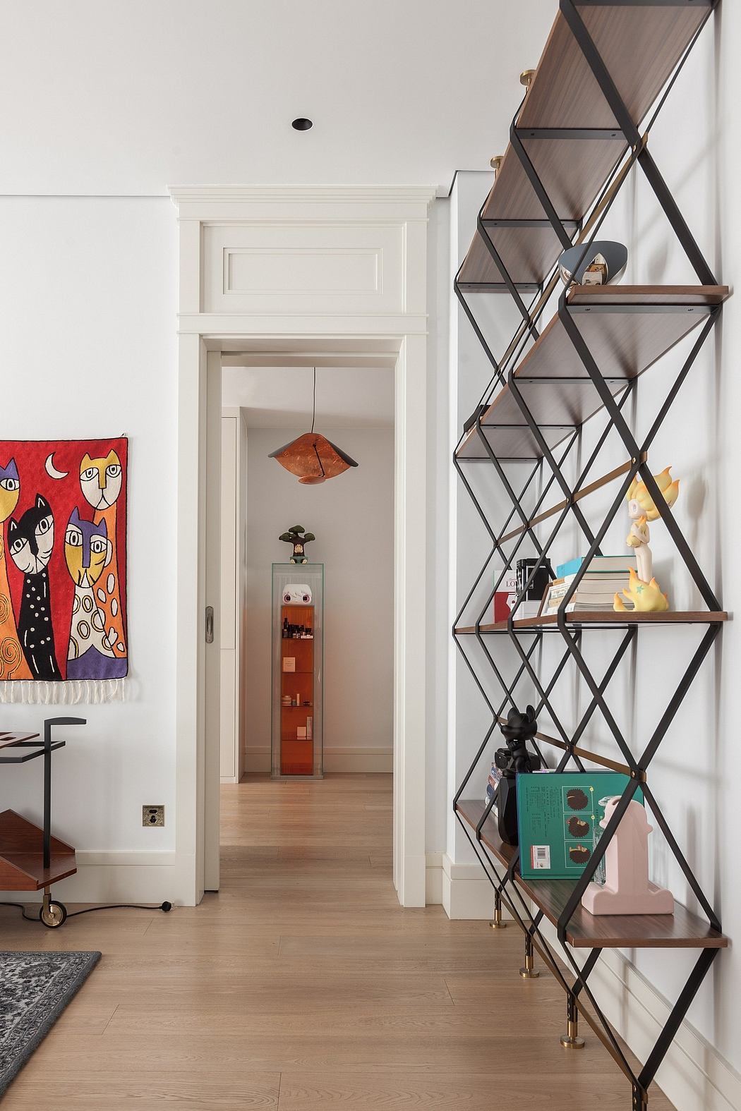 A white-walled room with a metal shelving unit, colorful artwork, and a door leading elsewhere.