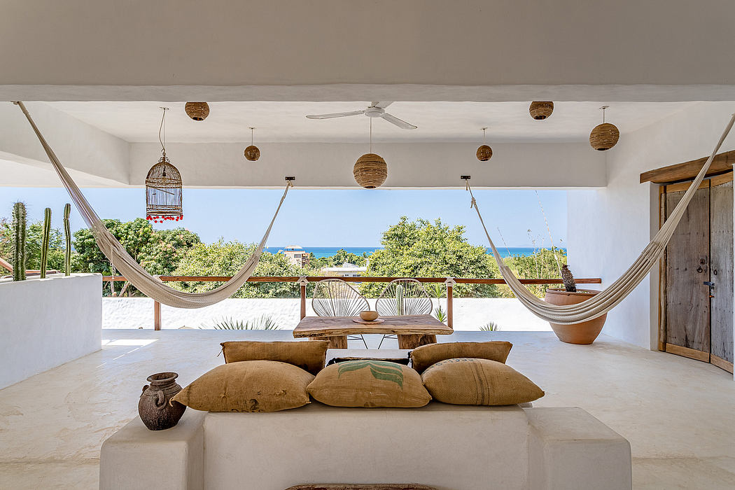 Coastal-themed living space with hammocks, textured cushions, and panoramic ocean views.