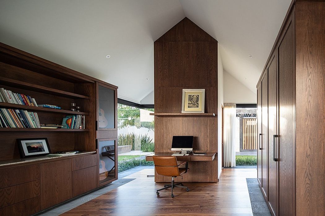 A cozy home office nook with a wooden fireplace and built-in shelves, overlooking a garden.