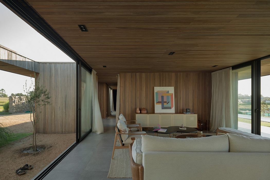 Spacious modern living room with expansive windows, wood-paneled walls, and minimalist decor.