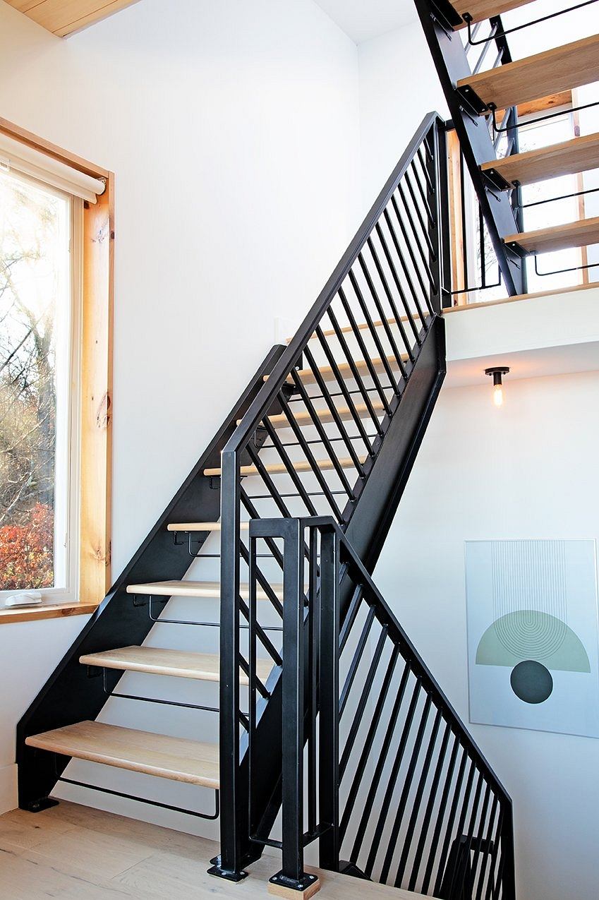 Sleek black metal staircase with wooden treads and modern art decor in the space.