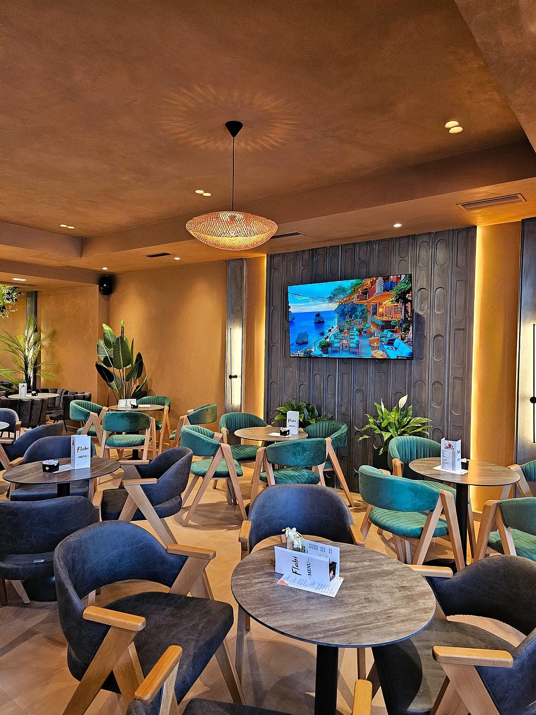 Cozy café interior with hanging pendant light, plush seating, and a large vibrant wall display.