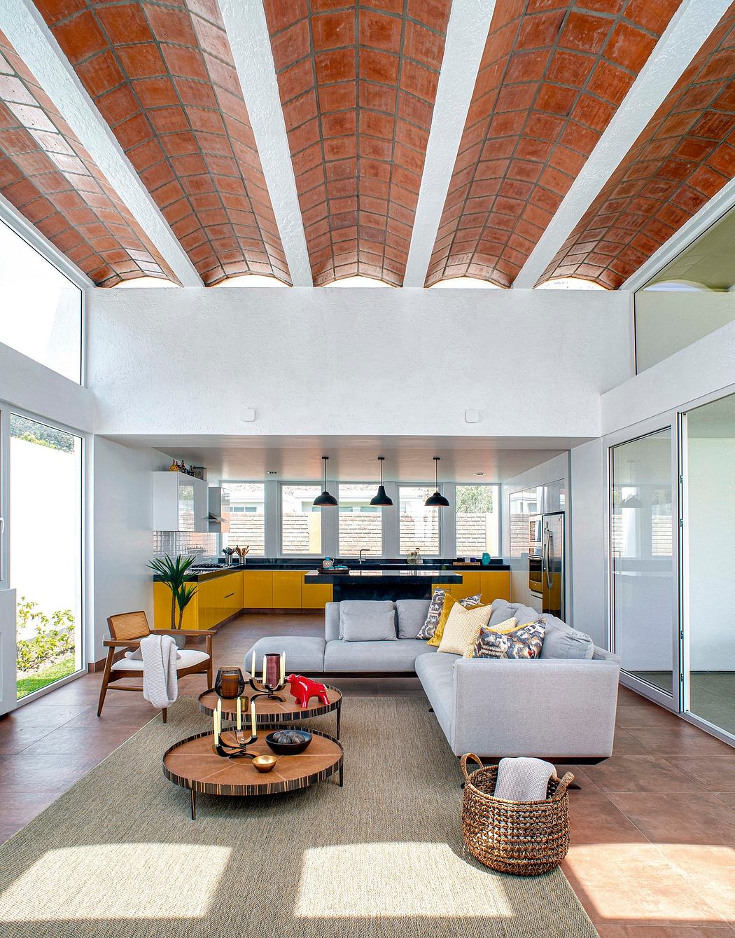 Spacious modern living area with vibrant yellow kitchen cabinets and exposed brick ceiling.