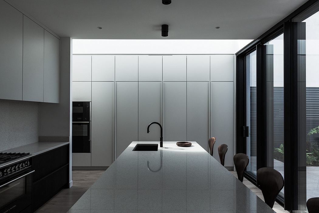 Sleek, minimalist kitchen featuring clean lines, white cabinetry, and a large central island.