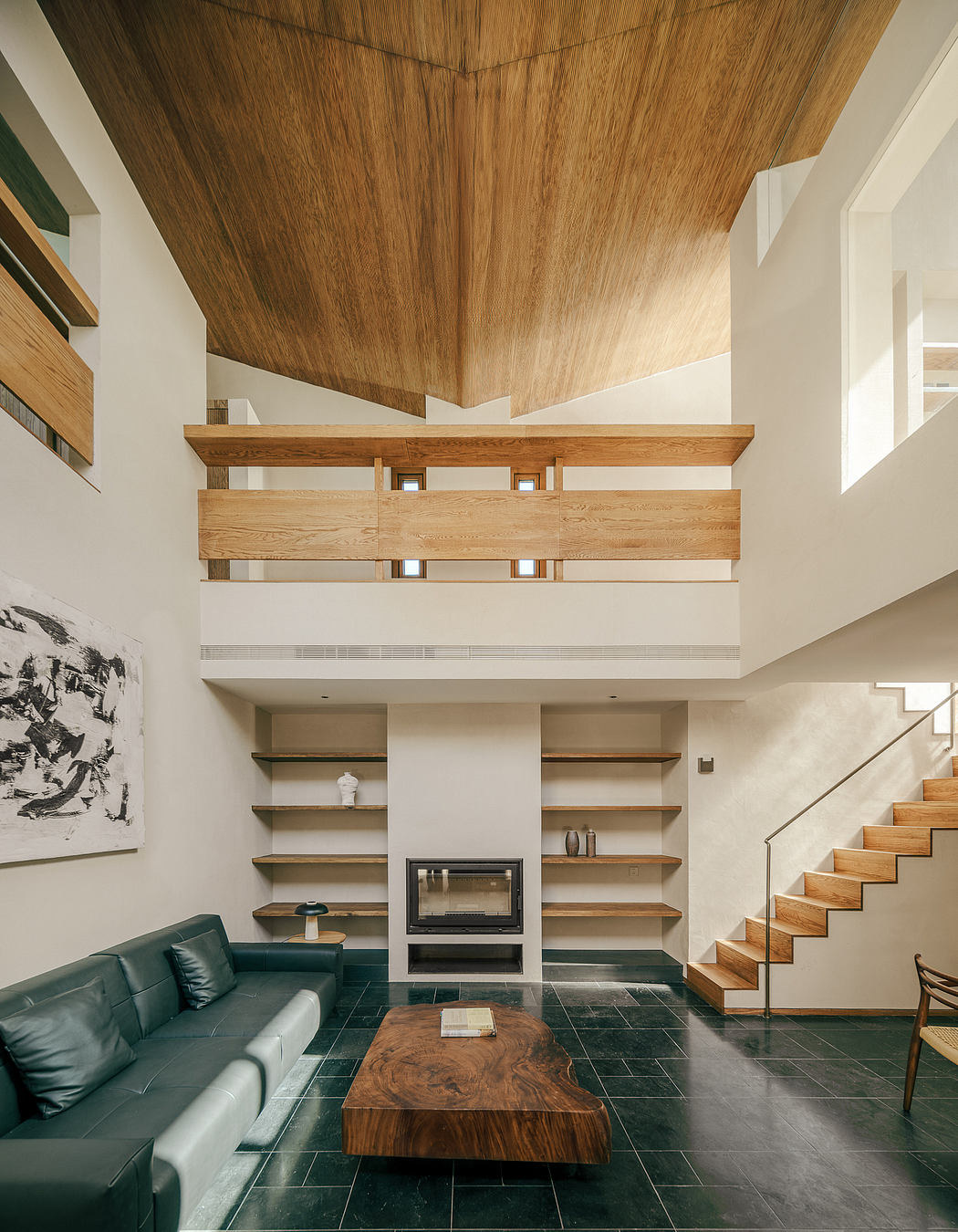 Spacious wood-paneled interior with modern fireplace, shelves, and staircase.