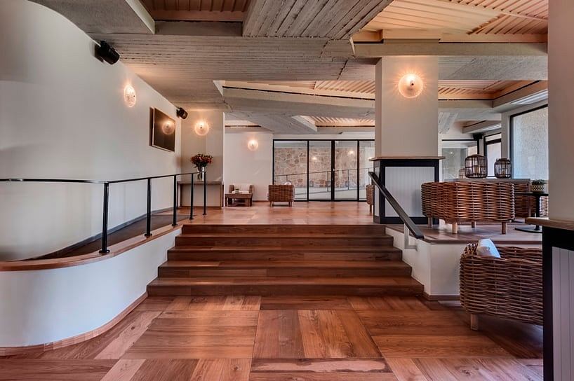 A spacious modern lobby with wooden floors, beamed ceilings, and decorative lighting.