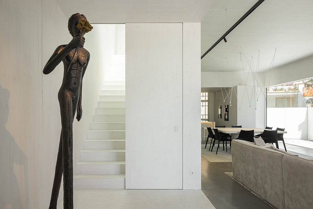 Minimalist interior with striking dark sculpture, clean lines, and open staircase.