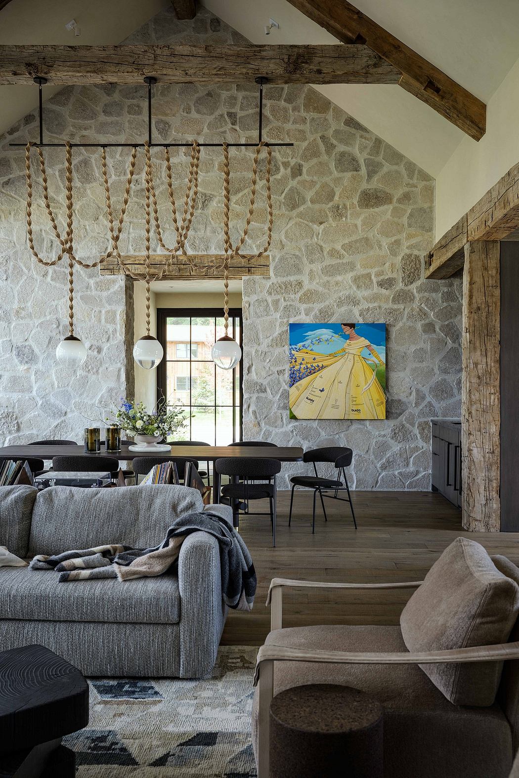 Rustic stone walls, wooden beams, and a contemporary art piece create a cozy ambiance.