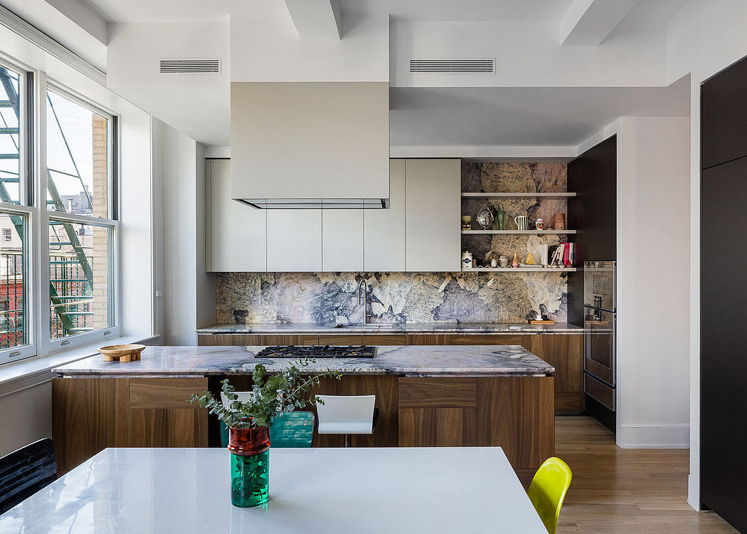 A bright, open kitchen with rustic stone walls, wooden cabinets, and a large marble countertop.