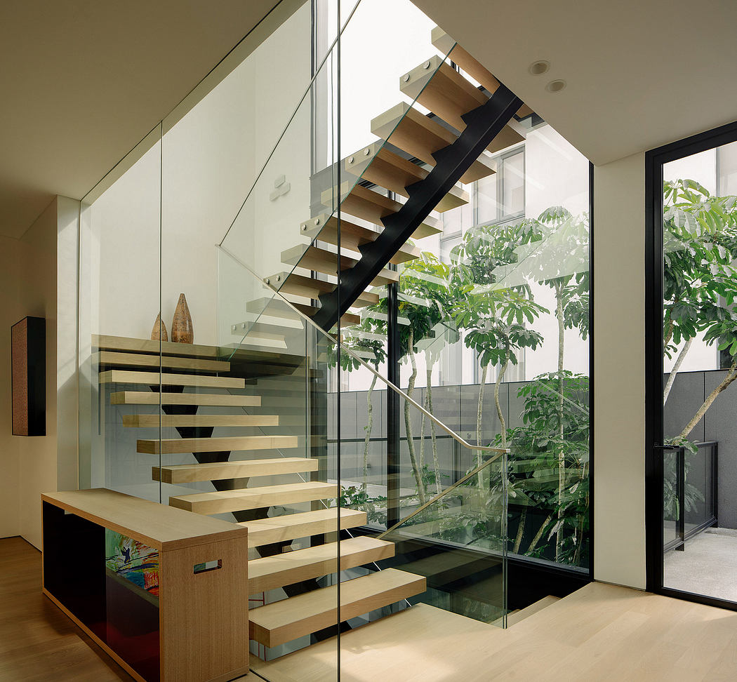 Floating staircase with wooden treads and glass balustrade, surrounded by lush greenery.