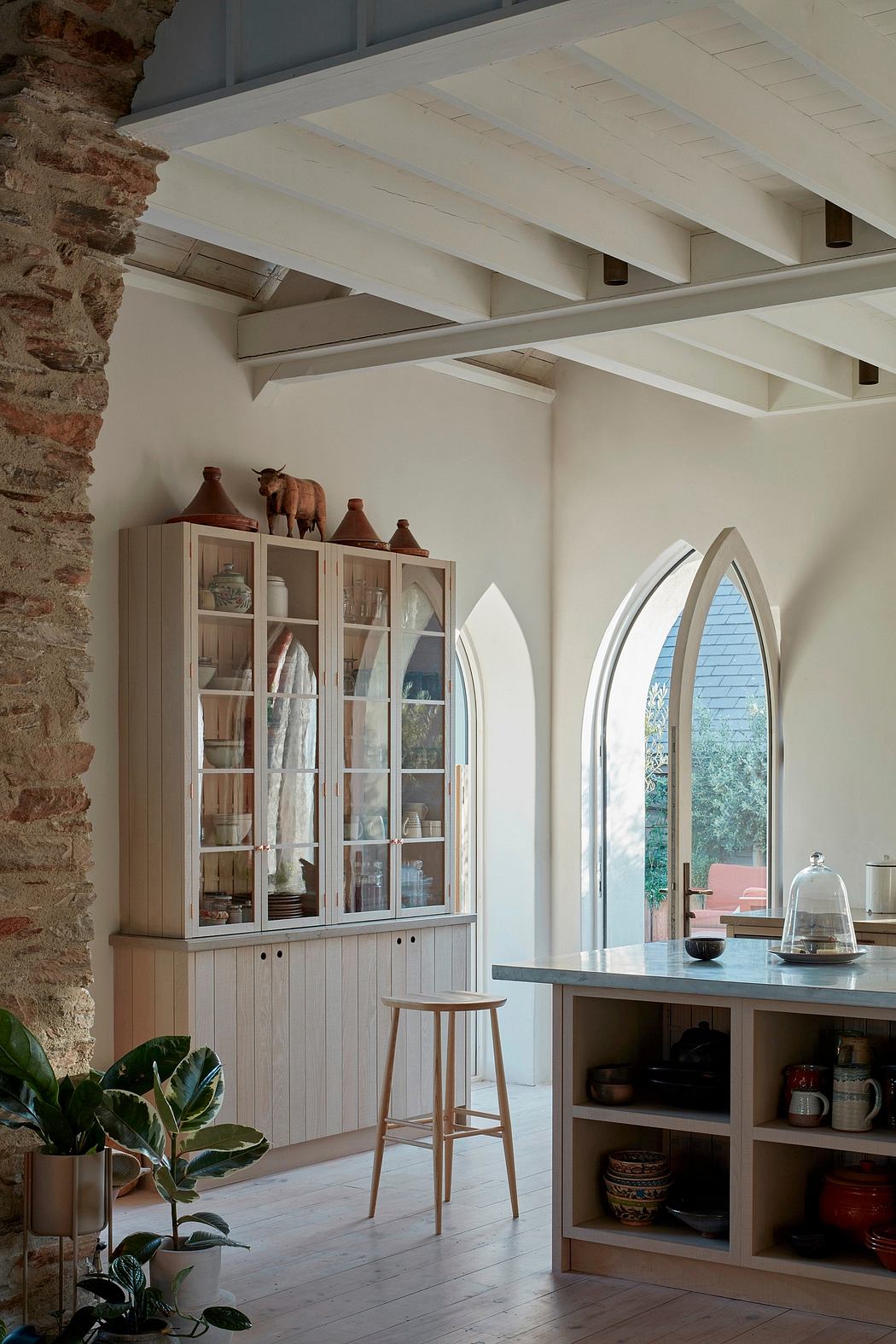 Rustic kitchen with arched windows, exposed brick, and a built-in wooden cabinetry.
