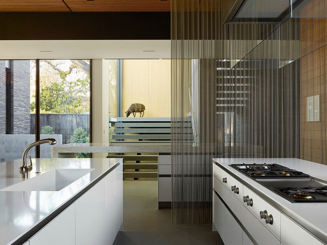 Sleek kitchen with large windows offering garden views, modern cabinetry, and decorative leopard figurine.