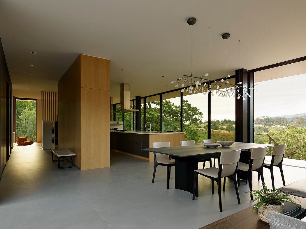 Minimalist open-plan interior featuring a large dining table, modern kitchen, and panoramic views.