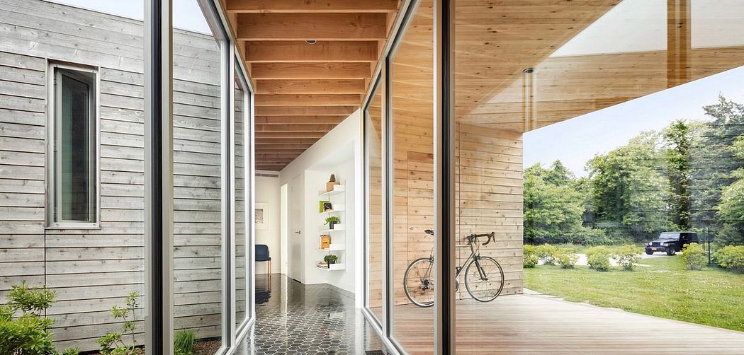 Spacious wood-paneled hallway with shelving, bicycle, and verdant outdoor views.