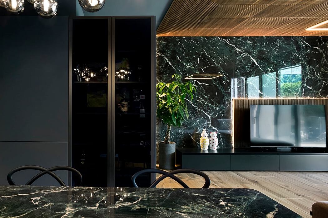 Elegant modern living room with sleek black cabinetry, verdant plants, and striking marble surfaces.