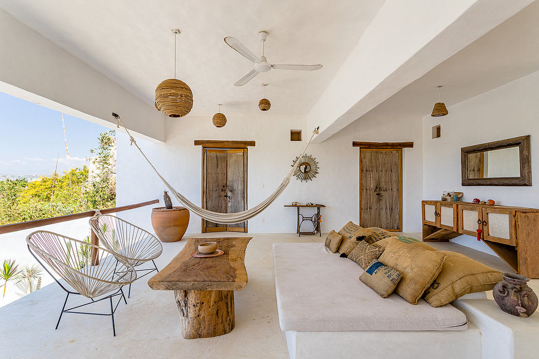 Rustic living room with wooden furniture, hammock, and natural lighting from large windows.