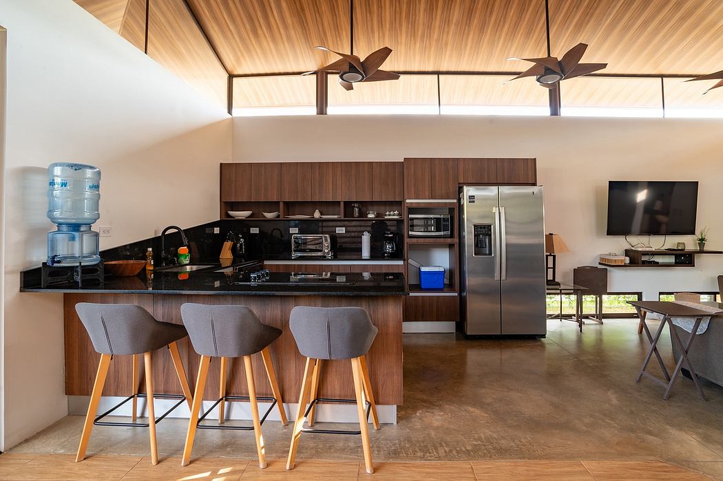 Modern open-plan kitchen with wood paneling, high ceilings, and sleek appliances.