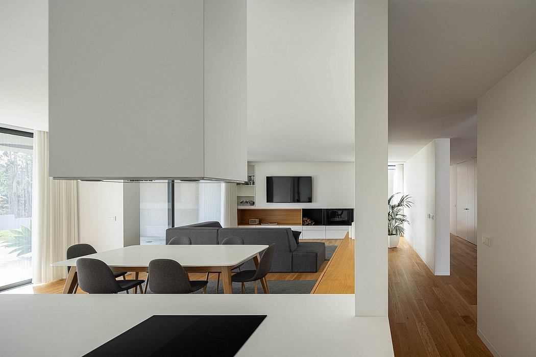 Contemporary open-plan living area with minimalist furnishings, wooden floors, and built-in entertainment unit.