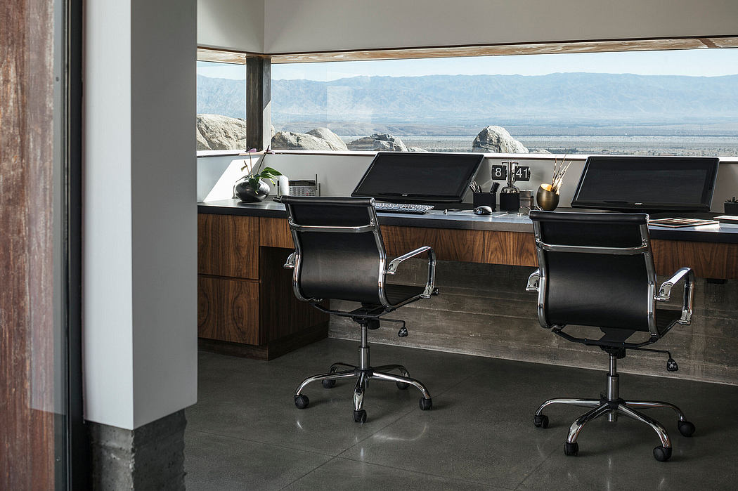 Modern workspace with sleek desk, chairs, and sweeping desert views through large windows.