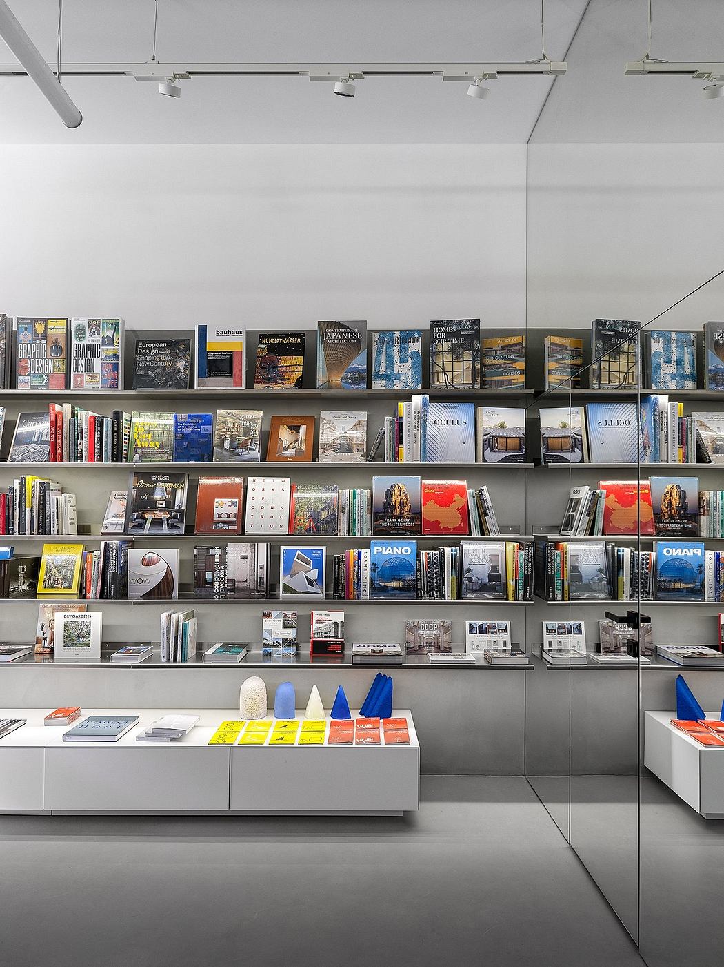 Well-organized bookshelves with diverse design publications, minimalist display units, and modern lighting elements.