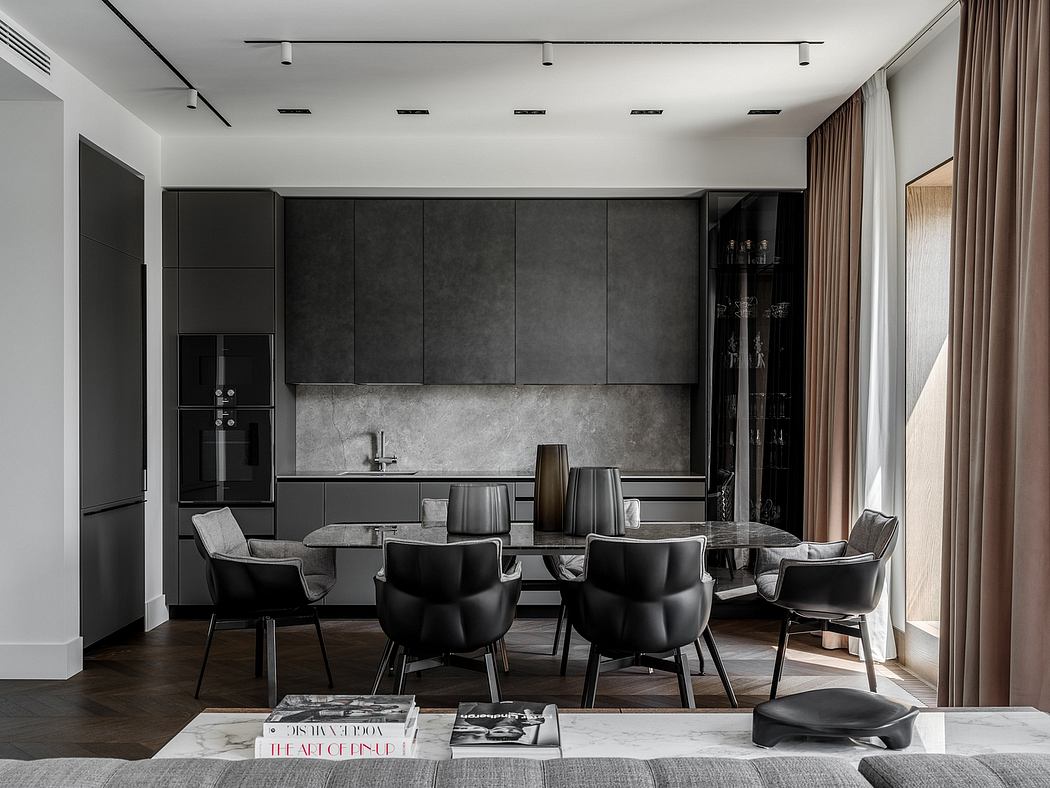 Sleek, modern kitchen with dark cabinets, marble backsplash, and a large dining table with black chairs.